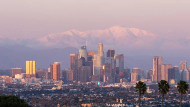 Gün batımında karla kaplı dağlarla kaplı Los Angeles silueti