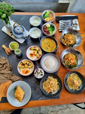 Bir masa dolusu yemek ve bir bardak şeftali çayı. Sahne davetkar ve sıcak. Karidesli spagetti, omletli nasi ve tavuklu karides..