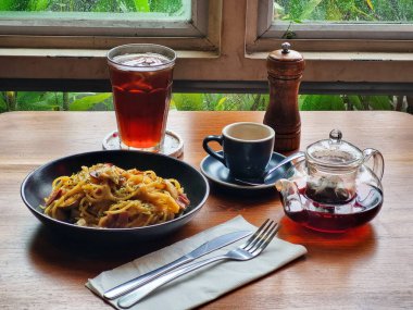 Yemek dolu bir masa. Sahne davetkar ve sıcak. Aglio soslu spagetti ve bir bardak şeftali çayı..