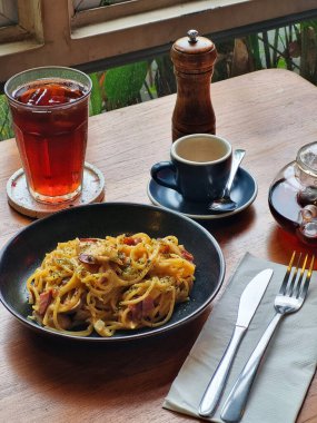 Yemek dolu bir masa. Sahne davetkar ve sıcak. Aglio soslu spagetti ve bir bardak şeftali çayı..