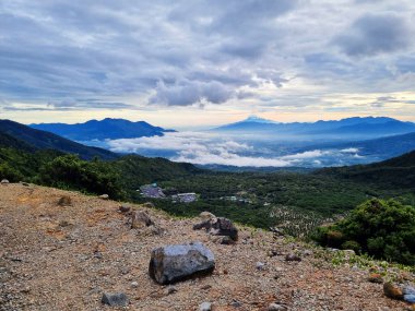 Güneşin doğuşunda Papandayan Dağı 'ndaki Tebing Soni' de Cikuray Dağı ve arkada Guntur Dağı ile sıcak bir atmosfer. Papandayan Dağı, Garut, Batı Java, Endonezya 'da yürüyüş için en sevilen yerlerden biridir..