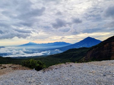 Güneşin doğuşunda Papandayan Dağı 'ndaki Tebing Soni' de Cikuray Dağı ve arkada Guntur Dağı ile sıcak bir atmosfer. Papandayan Dağı, Garut, Batı Java, Endonezya 'da yürüyüş için en sevilen yerlerden biridir..