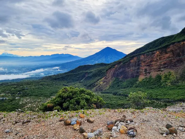Güneşin doğuşunda Papandayan Dağı 'ndaki Tebing Soni' de Cikuray Dağı ve arkada Guntur Dağı ile sıcak bir atmosfer. Papandayan Dağı, Garut, Batı Java, Endonezya 'da yürüyüş için en sevilen yerlerden biridir..