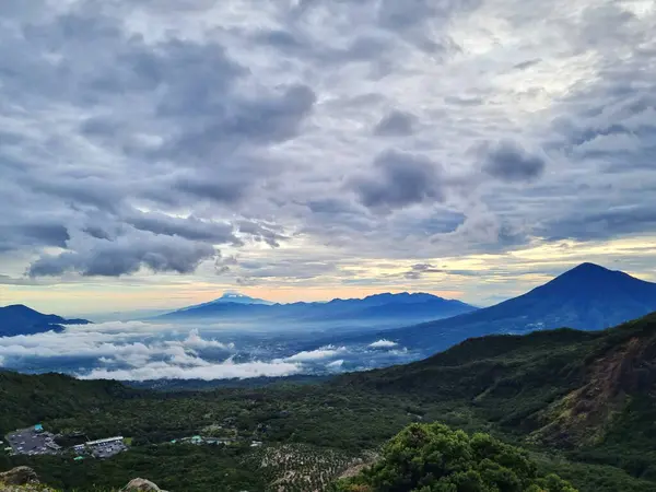 Güneşin doğuşunda Papandayan Dağı 'ndaki Tebing Soni' de Cikuray Dağı ve arkada Guntur Dağı ile sıcak bir atmosfer. Papandayan Dağı, Garut, Batı Java, Endonezya 'da yürüyüş için en sevilen yerlerden biridir..