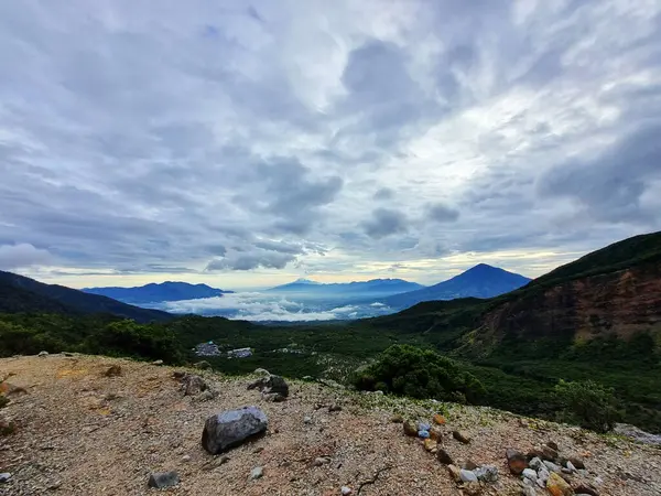 Güneşin doğuşunda Papandayan Dağı 'ndaki Tebing Soni' de Cikuray Dağı ve arkada Guntur Dağı ile sıcak bir atmosfer. Papandayan Dağı, Garut, Batı Java, Endonezya 'da yürüyüş için en sevilen yerlerden biridir..