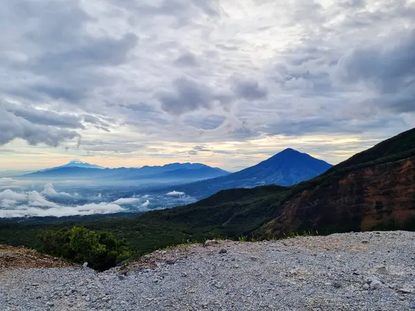Güneşin doğuşunda Papandayan Dağı 'ndaki Tebing Soni' de Cikuray Dağı ve arkada Guntur Dağı ile sıcak bir atmosfer. Papandayan Dağı, Garut, Batı Java, Endonezya 'da yürüyüş için en sevilen yerlerden biridir..