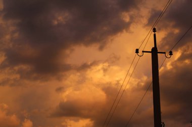 Power pole on the background of yellow clouds, optical illusion yellow sky, atmospheric photo power wire.