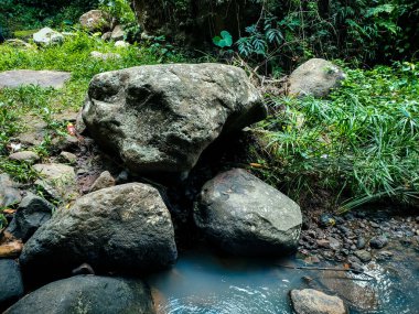 Büyük nehir taşları ve çevrelerindeki akan su, arka plandaki desenin güzel ve serin bir dokusunu oluşturuyor..