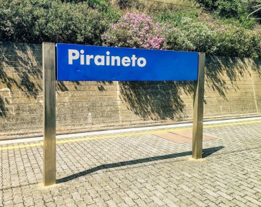 Close-up of the blue and white sign at the train station in Piraineto, Italy, on a sunny summer afternoon.. High quality photo