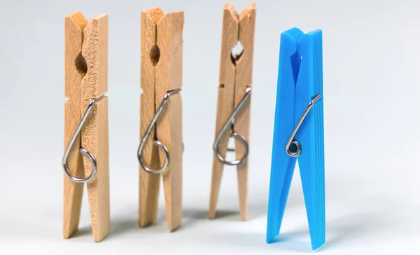 Blue clothespin on the background of ordinary wooden clothespins. The concept of being different, gender issue, standing out from the crowd, vision of man and woman.