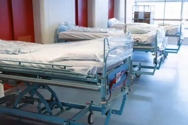 Clean hospital beds covered with film, ready for new patients. Hospital and nursing concept.