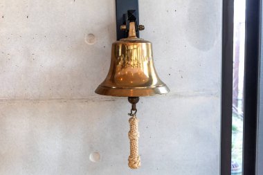 Brass bell on a gray wall indoors. High quality photo clipart