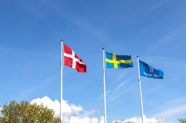 Denmark and Sweden flags and the flag of the port of the city of Ystad against blue sky. Scandinavian national flags clipart