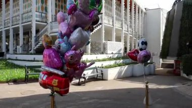 Birçok helyum balonu iplere bağlı ve rüzgarda sallanıyor. Balon satışı ve çocuklar için tatil kavramları. Yüksek kaliteli FullHD görüntüler