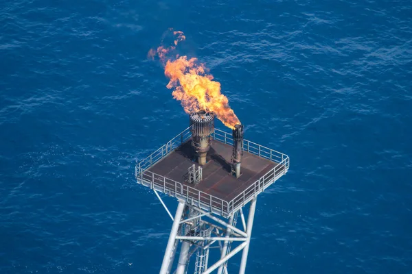 Offshore oil rig flare tip tower with flame filmed from the air.
