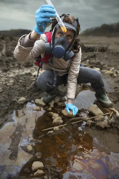 汚染された土壌サンプルの手のテスト管反応を非常に真剣に見る生物学者 — ストック写真
