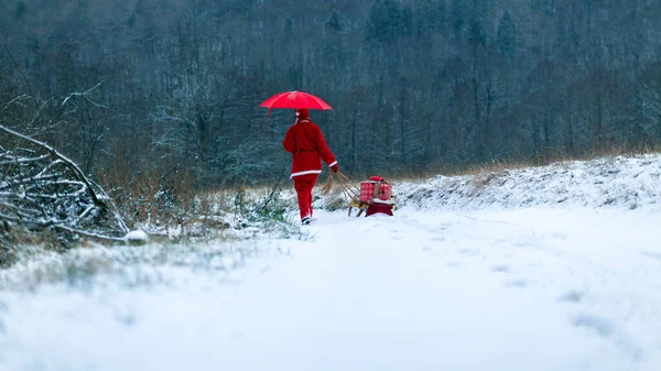 クリスマスウィンタータイムでカントリーランドの屋外を歩く赤い傘とサンタクロース — ストック写真