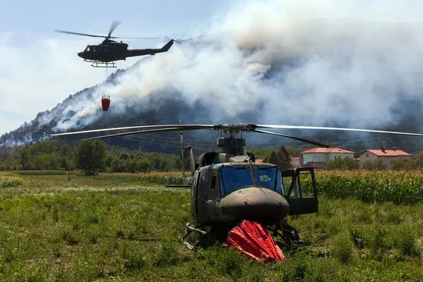 軍のヘリコプターは町に近い火を消すために消防士と協力します — ストック写真