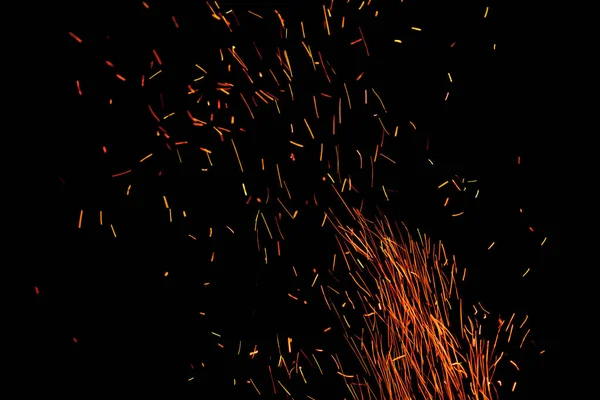Burning Red Fire Sparks fly away in a night sky from a large camp fire
