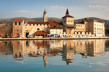 Trogir, Coatia - April 21, 2006: Reflections in the Adriatic and gentle morning light illuminate the timeless charm of this ancient Roman Empire tourist town in Dalmatia, protected by UNESCO clipart