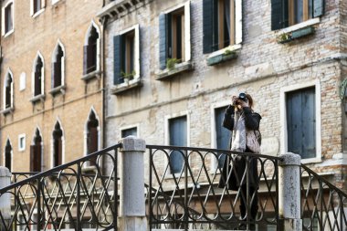 Yetişkin genç kadın turist Venedik 'te bir köprüden fotoğraf çekiyor.