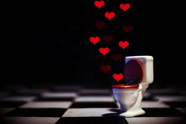 Doll House toilet WC that deliver love red hearts on a chess board concept of duality, deception and illusion. Christmas lights on dark background photographed all together trough a heart shape mask on lens with low dof F1.2 to obtain the effect of t
