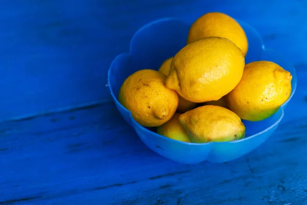 Yellow Lemons in a Blue Bowl on Blue Wooden table Background Copy Space