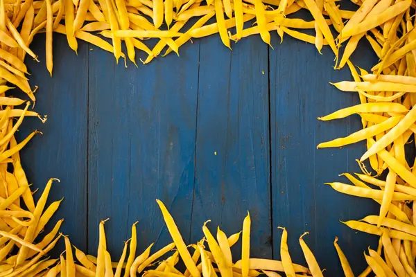 Yellow Frame from Beans in Pods on Blue Wooden Table Background