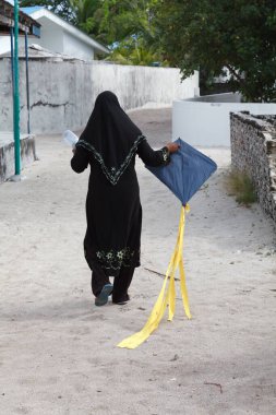 Bodufinolu, Maldives - 12. March 2010: Maldive Woman going to the beach to play with a handmade Kite