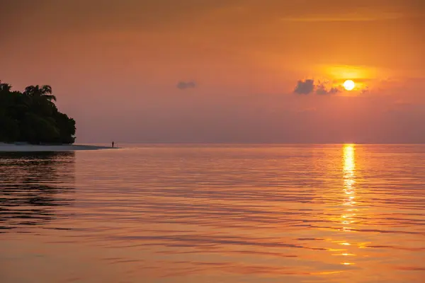 Morning Sunrise over sea from Maldives with human figure on beach enjoying it