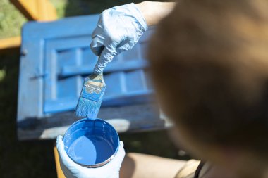 Eski ahşap pencerelerin yenilenmesinde çalışan bir kadın ressamın resmini mavi renklerle boyuyorum.