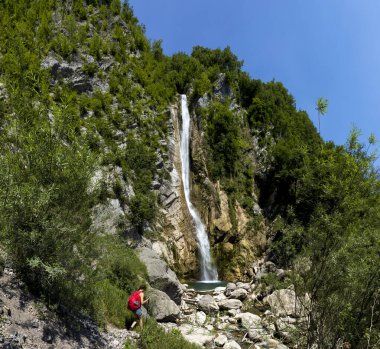 Kırmızı sırt çantalı Yetişkin Kadın Turist Yürüyüşçüsü Slovenya 'daki Görkemli Gregorcicev Şelalesini Keşfetti