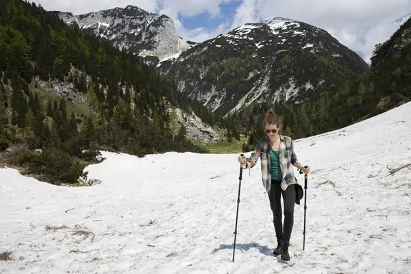Woman Hiking over Snow in Springtime Mountains