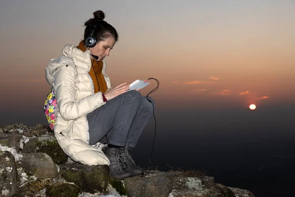 Adult Woman Working from Remote Location on Her Tablet and with Headphones at Sunset