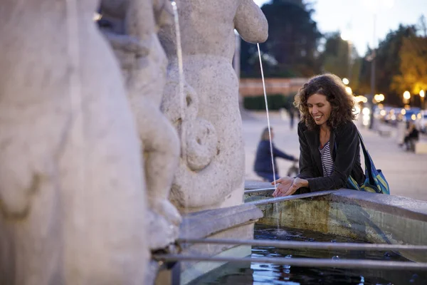 Smiling woman near a fountain in evening light