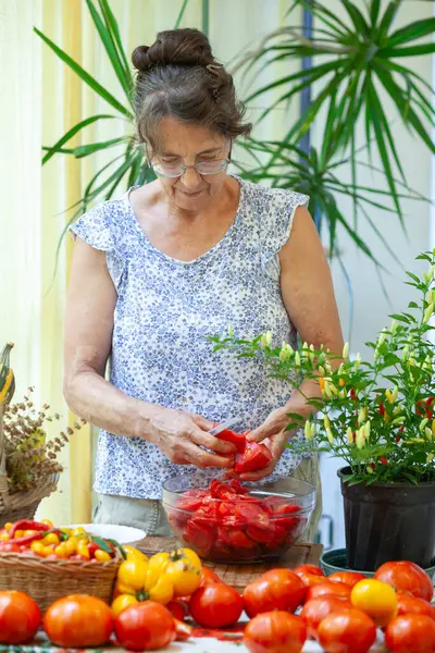 Senior Woman Cutting Abundance of Tomatoes fro Tomato Sauce on Domestic Table