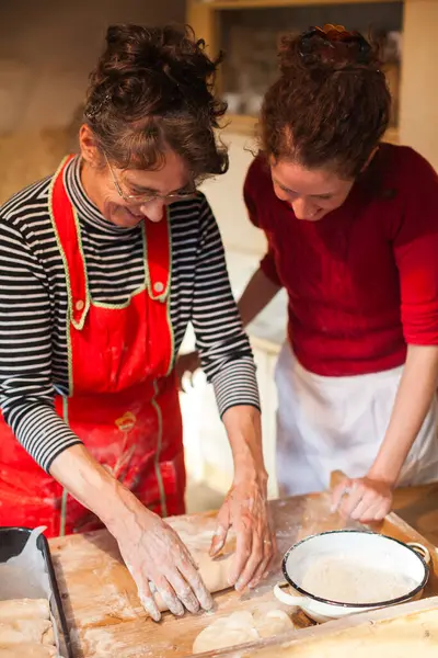 Senior Woman Instructing a Younger Trainee in the Art of Making Traditional Bread Dough in an Old House