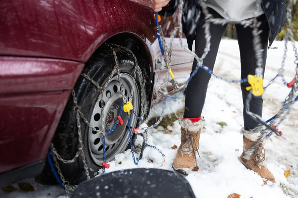 Woman Unhappily Setting Tire Chains in Icy and Unfriendly Conditions with Falling Snow