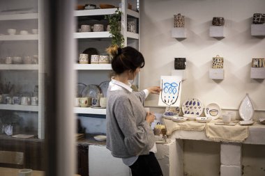 Stüdyo atölyesinde el yapımı ürünleri için tasarım seçen genç kadın seramik sanatçısı