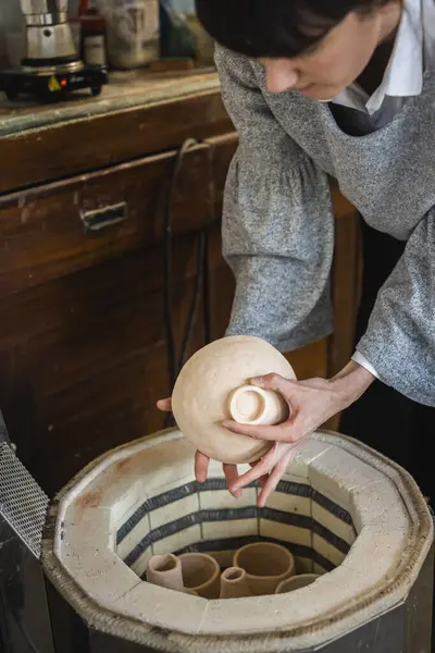 Female artisan putting ceramics in the kiln
