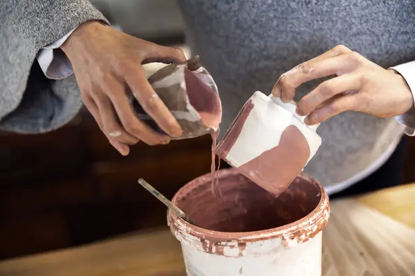 Ceramic Artist putting finish ceramic glaze on a crafted cup in her studio workshop
