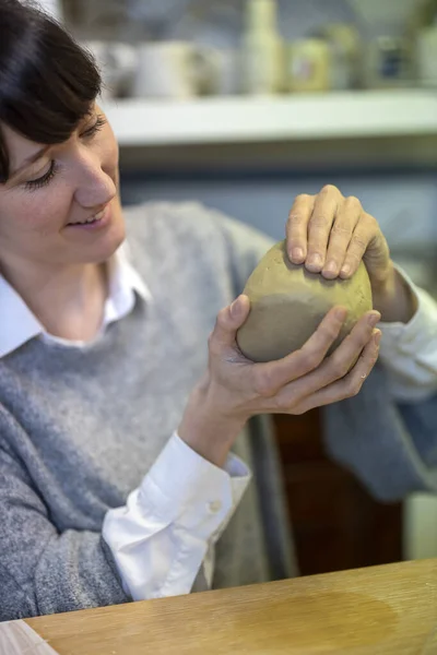 Ceramic Artist modelling a ceramic cup in her studio workshop