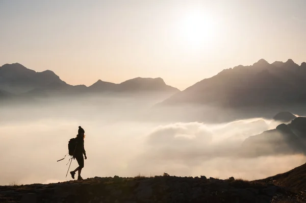 Silhouette of Female Hiker Above Clouds in High Mountains Landscape