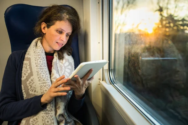 Adult Woman Reading on a Tablet While Travel With a Train