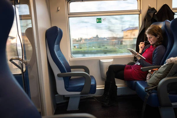 Handsome Woman Sitting on a Public Transport Train and Following a Training Class Program on a Tablet