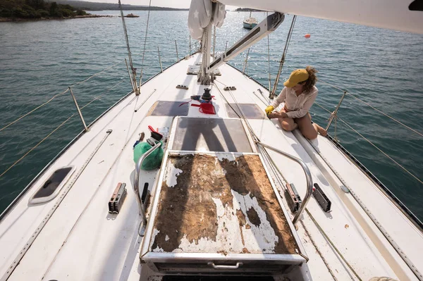 Working Vacation on an Old Sailboat for Adult Serene Woman Using Time to Sunbath and Repairing - Restoring her sail boat on the sea with Confidence