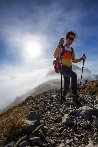 Confident Adult Woman Climber Ascent Hike on European Alps Mountain in Changing Weather
