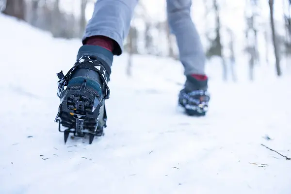 Crampons on Hiking Boots from Low Angle View in an Action on Icy Snow Covered Mountain Trail