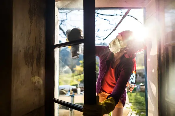 Adult Caucasian Woman Cleaning Old House Windows With Face Mask During Renovation Works