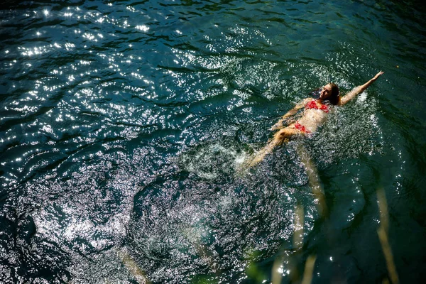 Adult Caucasian Woman Swimming in a River Lagoon in Red Bikini and Enjoying Summer Vacations in Mountains